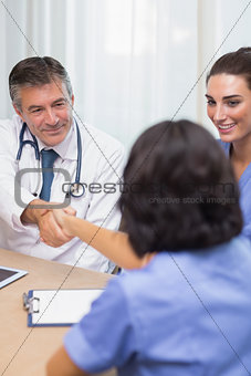 Smiling doctor shaking nurses hand