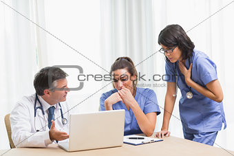 Doctor showing nurses something sad on laptop