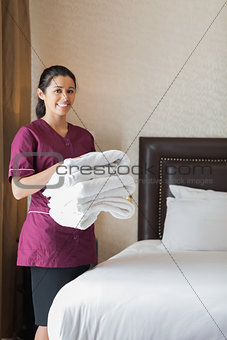 Smiling hotel maid holding towels