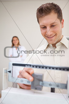 Man adjusting scale while being supervised