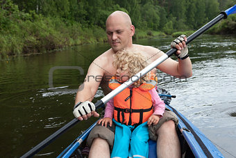 Dad and little daughter are sailing, kayaking on the river.