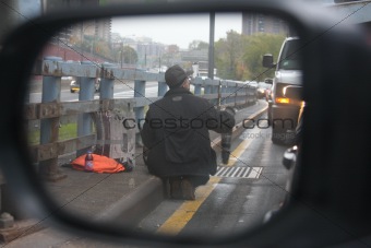 Side view mirror view of a beggar on road