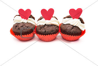 Three chocolate valentines cupcake with heart decorations and cream