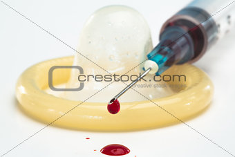 Rolled up condom and hypodermic needle dripping blood