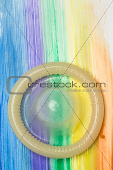 Rolled up condom on rainbow brush stroke