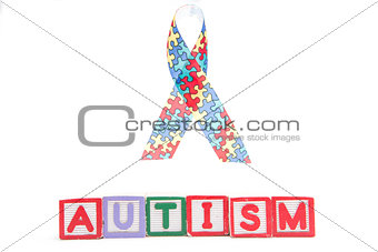 Autism awareness ribbon above letter blocks spelling autism