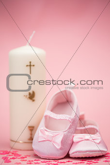 Pink baby booties with christening candle