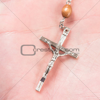 Cross of rosary beads in hand