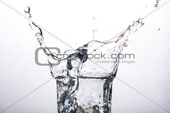 Close up on ice cube falling into a glass