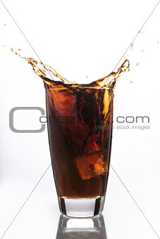 Ice cube falling into glass of soda