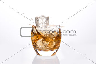 Ice cube falling in a tumbler of whiskey