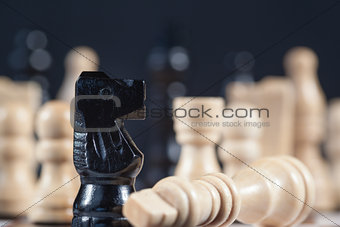 Fallen white chess piece lying next to black knight