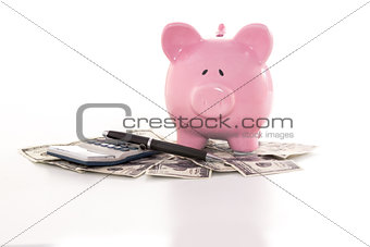 Piggy bank beside calculator on dollars