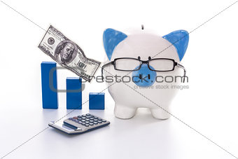 Blue and white piggy bank wearing glasses with blue graph model and calculator