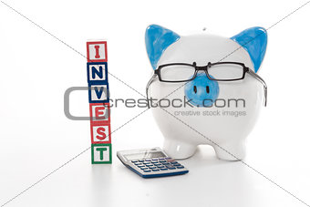 Blue and white piggy bank wearing glasses with invest building blocks