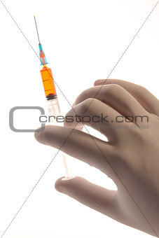 Gloved hand holding a syringe