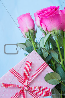 Bouquet of pink roses in vase with pink gift