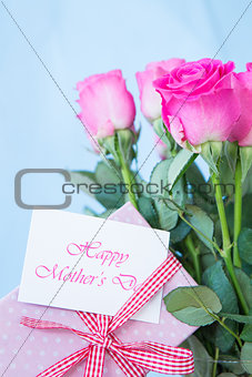 Bouquet of pink roses in vase with pink gift and mothers day message