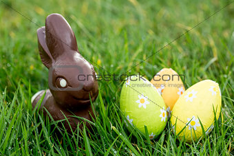 Chocolate bunny in the grass with easter eggs