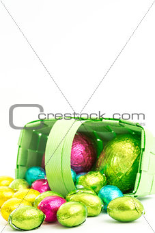 Foil wrapped easter eggs spilling from a basket