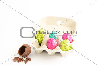 Carton of easter eggs with one broken on surface