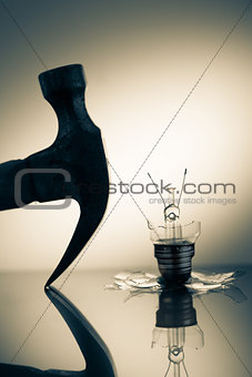 Hammer silhouette beside broken light bulb