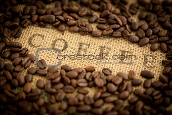 Coffee beans surrounding coffee stamped on sack