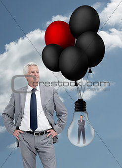 Businessman standing next to businesswoman inside light bulb held by balloons
