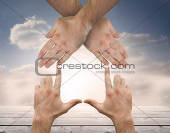 Hands crossed representing a house with blue sky