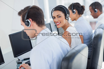 Smiling call centre employee looking over shoulder
