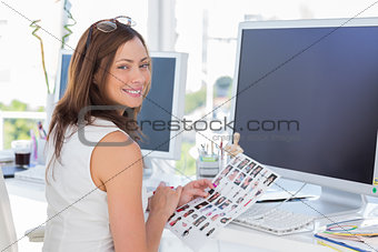 Editor looking over shoulder at camera at her desk