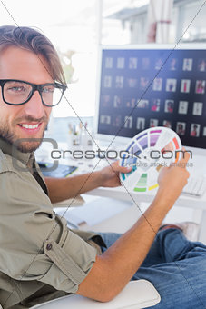 Photo editor holding colour wheel and smiling at camera