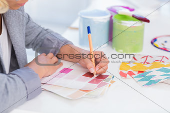 Pretty interior designer drawing on colour samples
