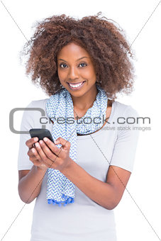 Smiling woman looking at camera and typing a text message