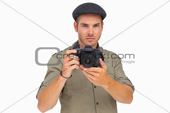 Serious man in peaked cap taking photo