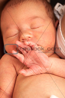 Newborn baby sleeping in mother's arms