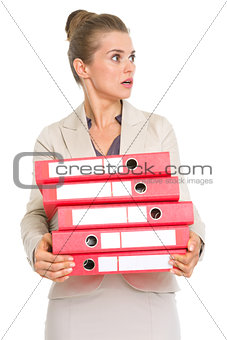 Surprised business woman holding stack of folders and looking on