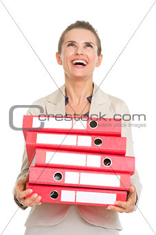 Surprised business woman holding stack of folders and looking up