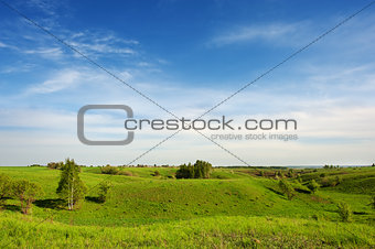 Hilly green meadow and clouds in the sky