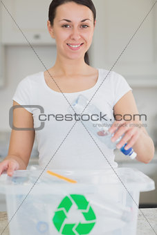 Woman happily throwing bottle into recycling bin
