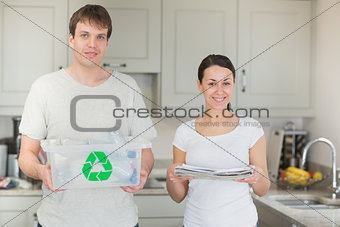Couple holding recycling bin and newspapers