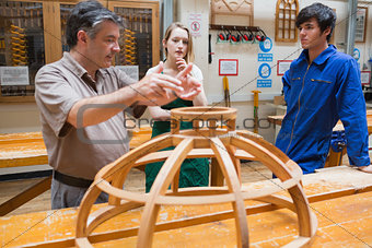 Two students and an explaining teacher in a woodwork class