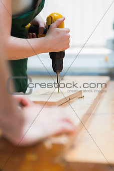 Drilling a hole in a wooden board on the workbench