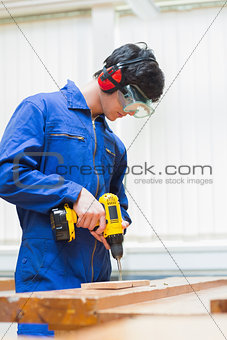 Student of a woodworking class drilling a hole
