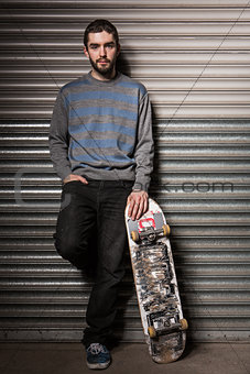 Attractive skater leaning against metal shutters
