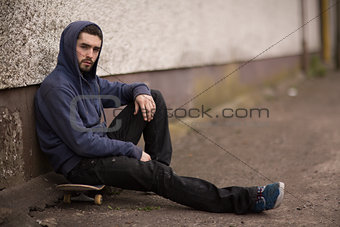 Skater taking a break outside the skate park and looking at camera