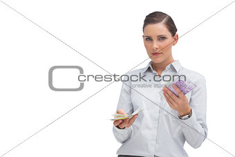 Businesswoman holding wads of cash and looking at camera