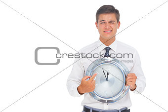 Worried businessman holding and pointing at clock