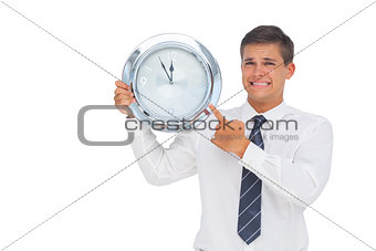 Anxious businessman holding and showing a clock