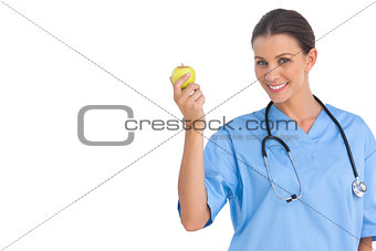 Happy surgeon holding an apple and smiling at camera